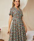 Woman wearing a belted fit-and-flare dress in a colorful meadow floral print on a navy background.
