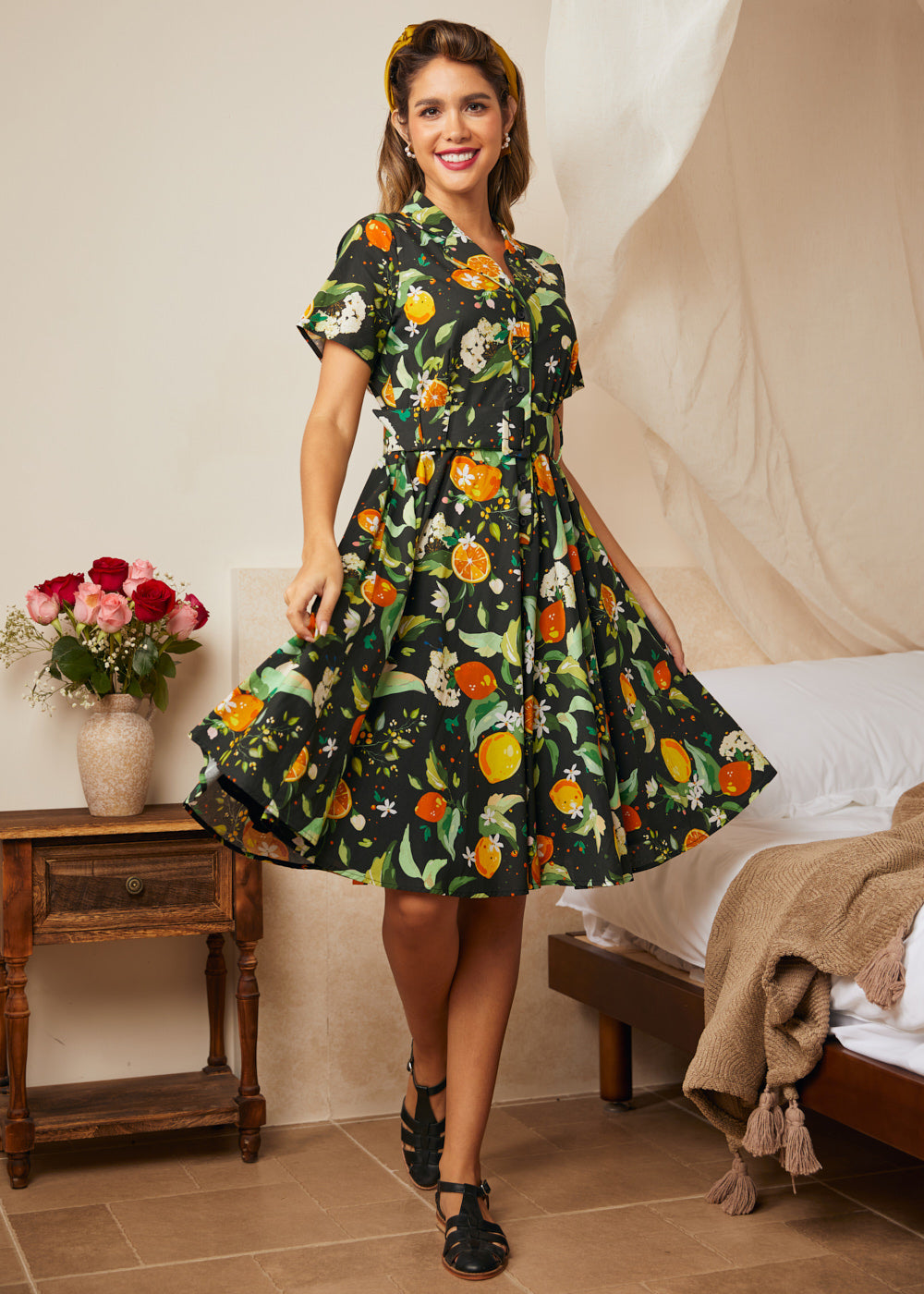 Woman wearing a black citrus print fit-and-flare shirt dress with a removable matching belt.