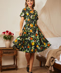 Woman wearing a black citrus print fit-and-flare shirt dress with a removable matching belt.