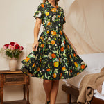 Woman wearing a black citrus print fit-and-flare shirt dress with a removable matching belt.