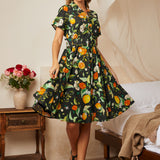 Woman wearing a black citrus print fit-and-flare shirt dress with a removable matching belt.