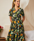 Woman wearing a belted citrus grove fit-and-flare dress with a full skirt.