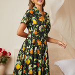 Woman wearing a vintage citrus blossom fit-and-flare dress with a gathered skirt.