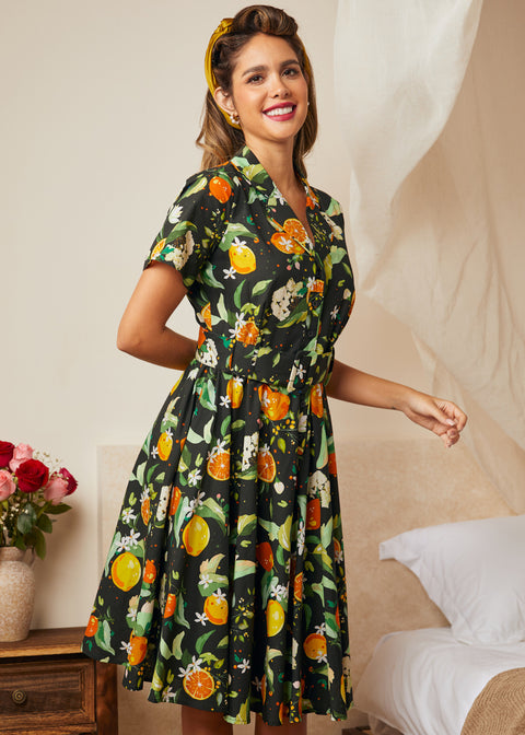 Woman wearing a vintage citrus blossom fit-and-flare dress with a gathered skirt.