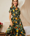 Woman wearing a retro-inspired black botanical fruit print dress with short sleeves.