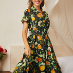 Woman wearing a retro-inspired black botanical fruit print dress with short sleeves.