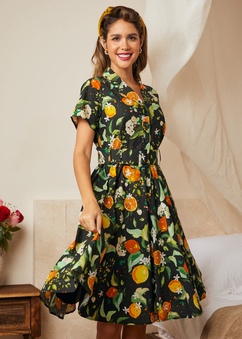 Woman wearing a retro-inspired black botanical fruit print dress with short sleeves.