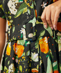 Close-up of the removable fabric belt and functional button-front bodice on a citrus print dress.