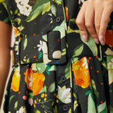 Close-up of the removable fabric belt and functional button-front bodice on a citrus print dress.