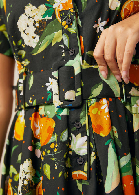 Close-up of the removable fabric belt and functional button-front bodice on a citrus print dress.