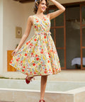Woman wearing a vintage-inspired faux wrap cotton midi dress with a colorful wildflower print and removable tie belt.