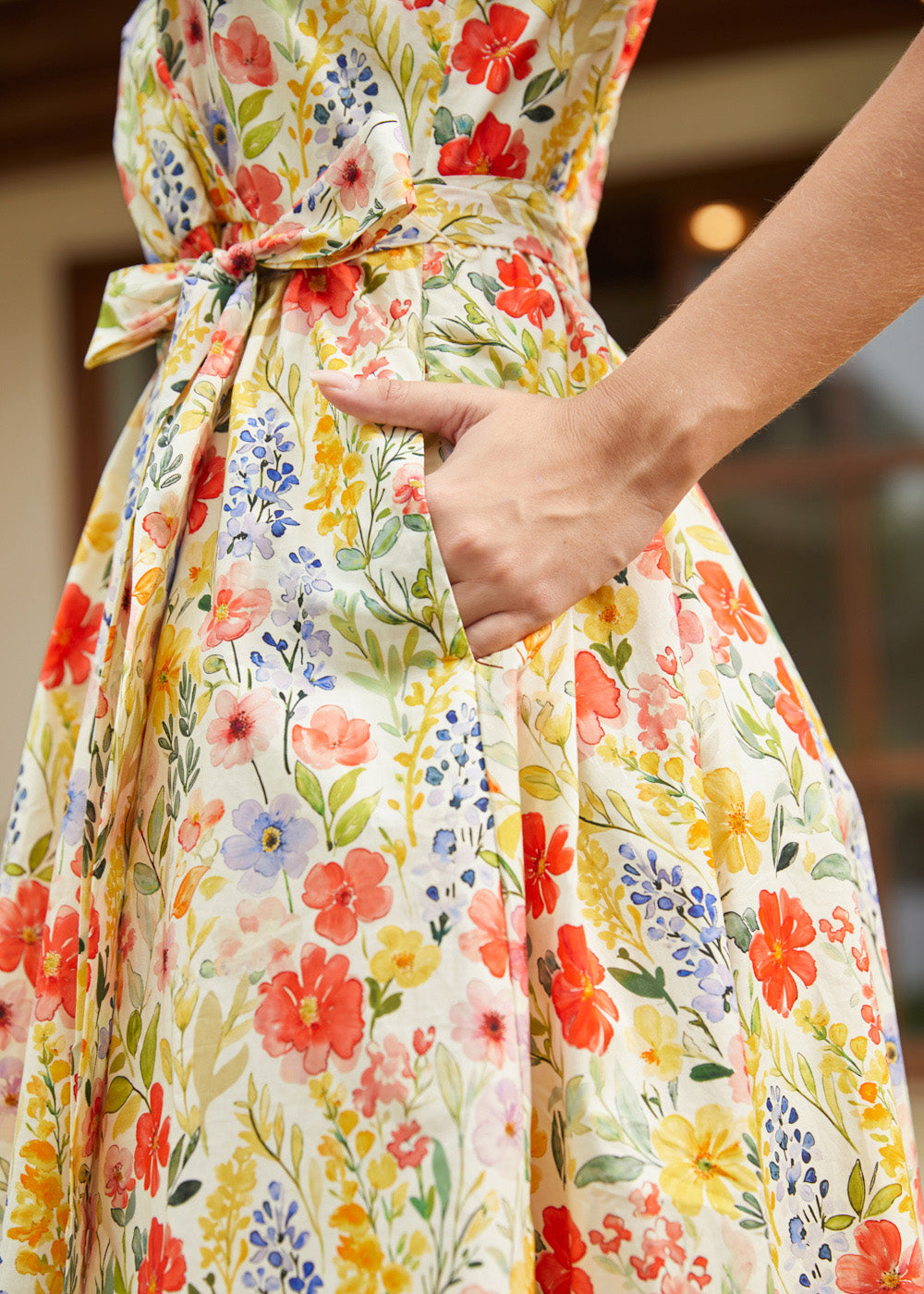 Detail of the side seam pocket and self-tie waist belt on a cotton floral midi dress.