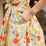 Detail of the side seam pocket and self-tie waist belt on a cotton floral midi dress.