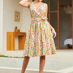 Woman wearing a sleeveless fit-and-flare dress featuring a playful fruit stripe novelty print.