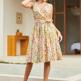 Woman wearing a sleeveless fit-and-flare dress featuring a playful fruit stripe novelty print.