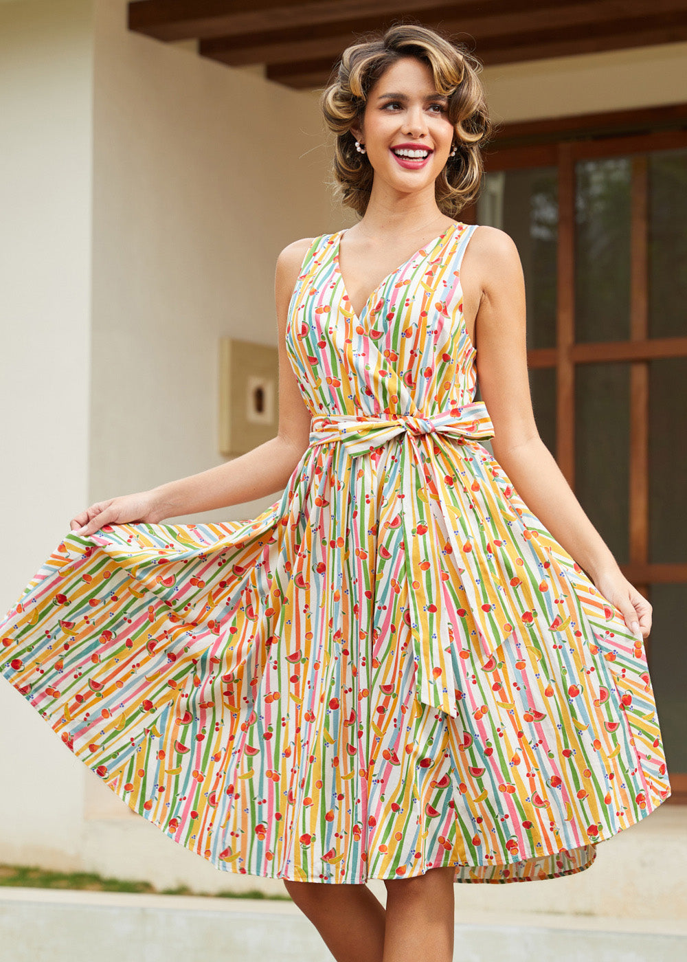 Woman styling a whimsical fruit print cotton dress with side pockets and a flattering faux wrap silhouette.