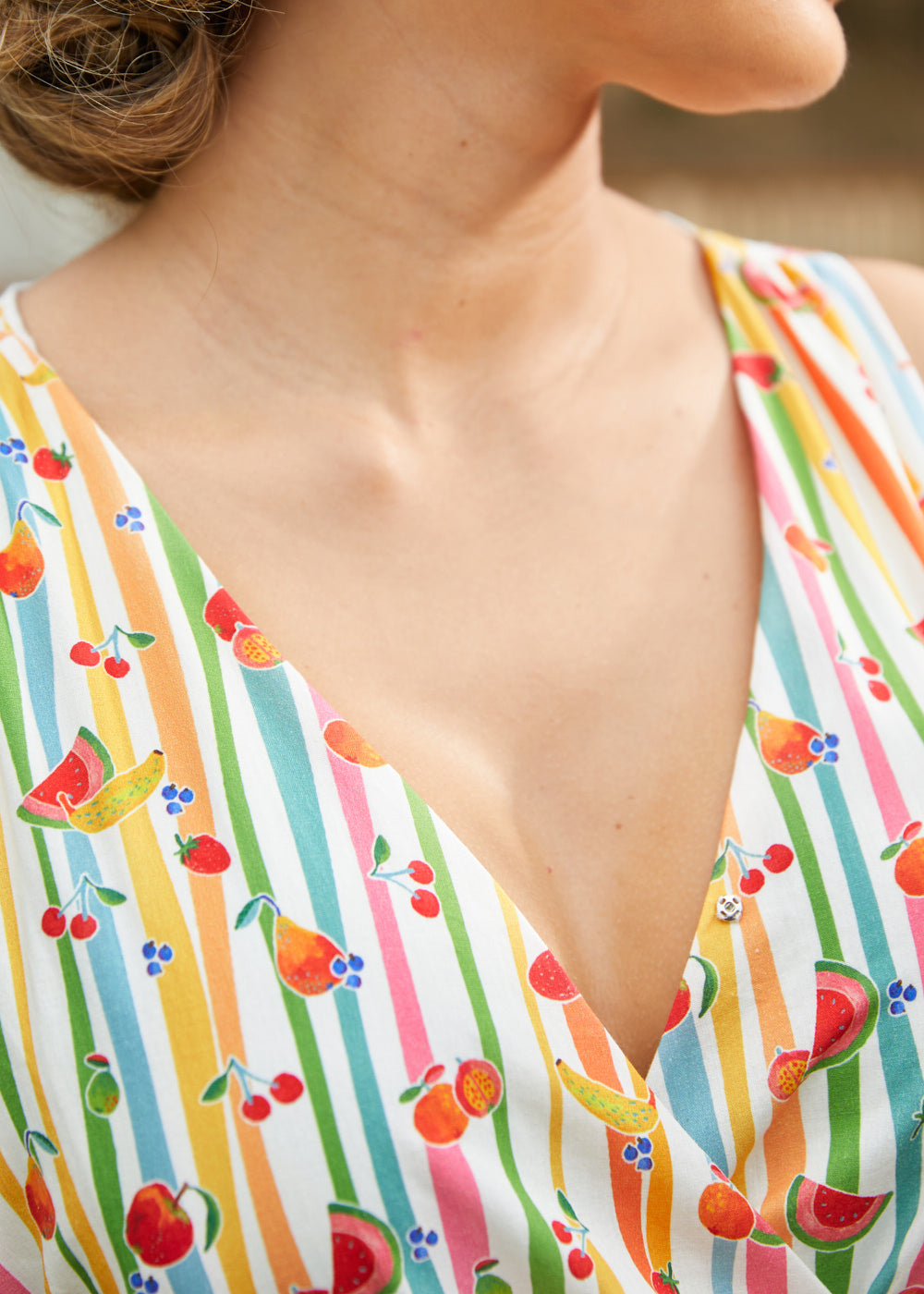 Close-up of the V-neck faux wrap bodice on a summer dress with a whimsical fruit stripe print.