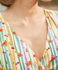 Close-up of the V-neck faux wrap bodice on a summer dress with a whimsical fruit stripe print.