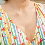Close-up of the V-neck faux wrap bodice on a summer dress with a whimsical fruit stripe print.