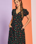 Woman wearing black cherry print vintage-inspired midi dress with puff sleeves and pockets