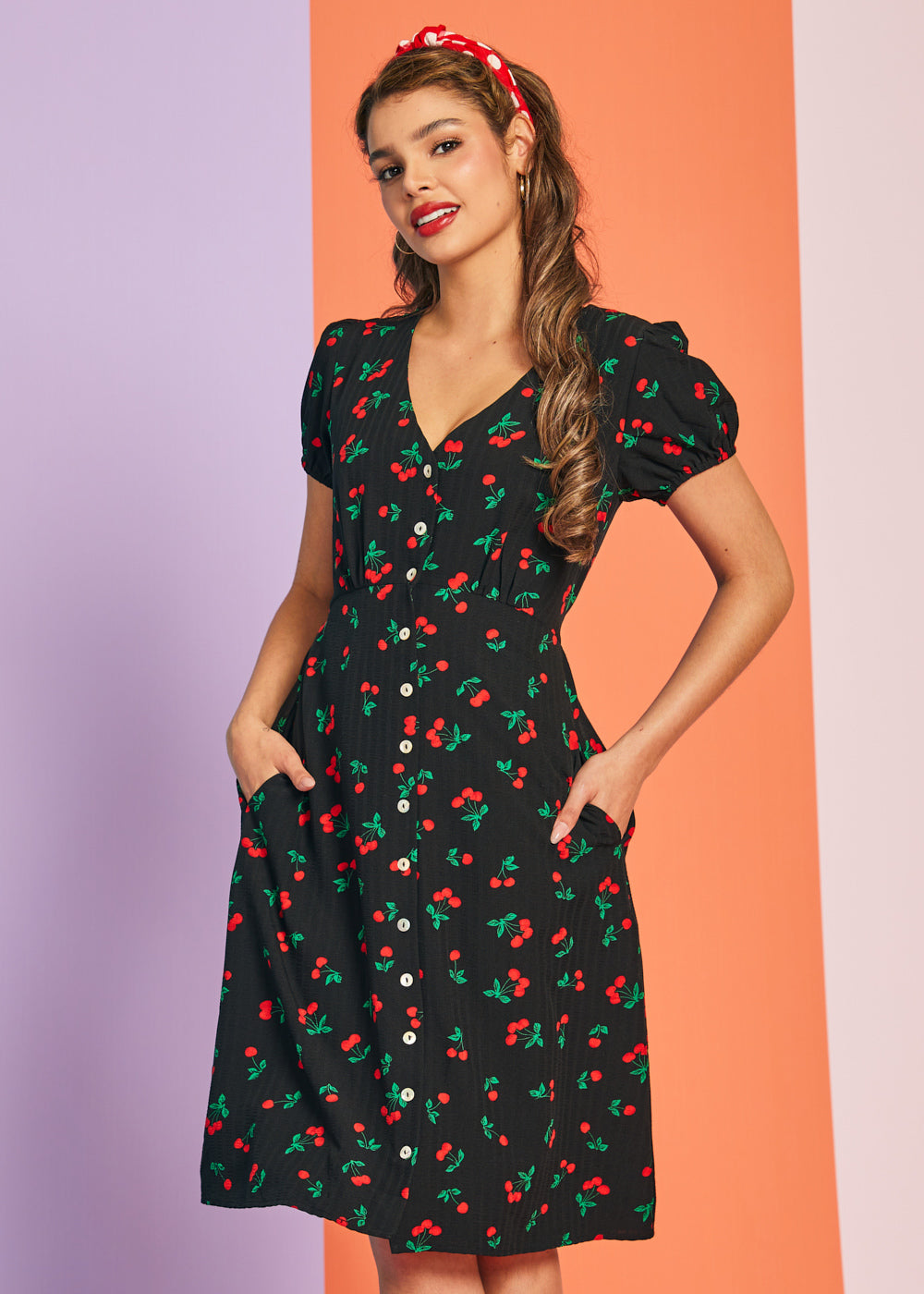 Woman wearing black cherry print vintage-inspired midi dress with puff sleeves and pockets