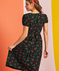 Woman twirling in retro cherry print midi dress with puff sleeves