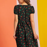 Back view of woman wearing black cherry print midi dress with waist tie