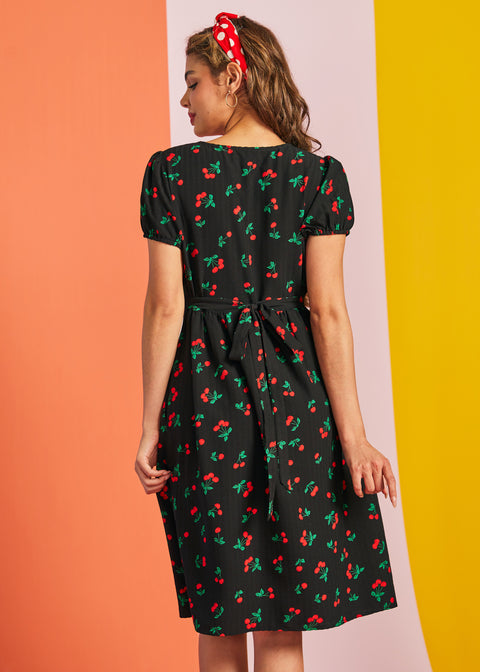 Back view of woman wearing black cherry print midi dress with waist tie