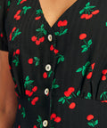 Close-up of cherry print fabric and button-front detail on black rockabilly dress