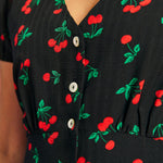 Close-up of cherry print fabric and button-front detail on black rockabilly dress