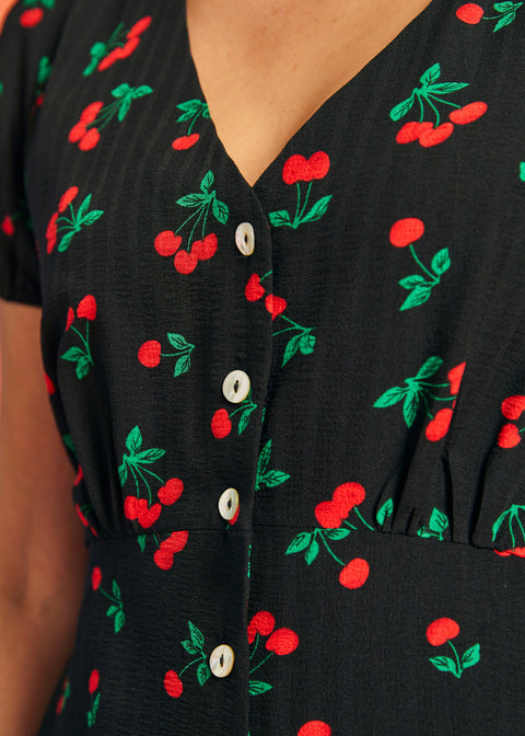 Close-up of cherry print fabric and button-front detail on black rockabilly dress