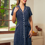 Woman wearing a vintage style navy blue dress with white polka dots and button front