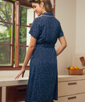 Back view of a woman in a blue polka dot summer dress standing in a kitchen.