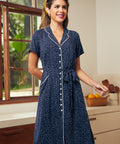 Woman wearing a classic polka dot midi dress with contrast piping and a removable sash belt for a timeless everyday look.