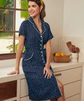 Woman wearing a navy blue polka dot dress with white trim in a kitchen.