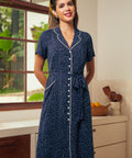 Woman wearing a navy blue polka dot dress with short sleeves and a belted waist