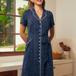 Woman wearing a navy blue polka dot dress with short sleeves and a belted waist