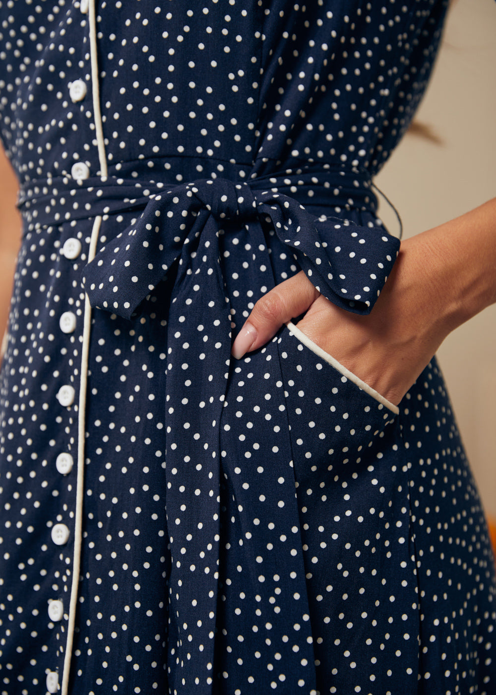 Close up of pockets on a navy blue dress with white polka dots and buttons