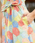 Close-up of a belted dress with a colorful geometric umbrella print, and side pockets.