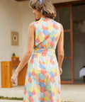 Back view of a woman wearing a sleeveless knee-length dress with a colorful retro umbrella pattern.