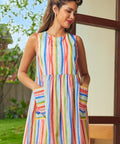 Woman wearing a rainbow stripe sleeveless mini dress with oversized patch pockets
