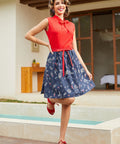 Woman in a vintage style retro red top and blue skirt standing by a poolside.
