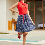 Woman in a vintage style retro red top and blue skirt standing by a poolside.