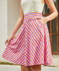 Woman wearing a colorful striped skirt with a neutral background