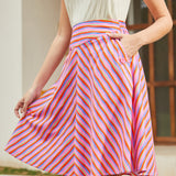 Woman wearing a colorful striped skirt with a neutral background