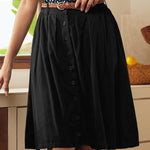 Woman wearing black vintage-inspired button front skirt with braided belt and polka dot blouse