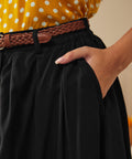 Close-up of black gathered skirt with side pocket and braided belt detail