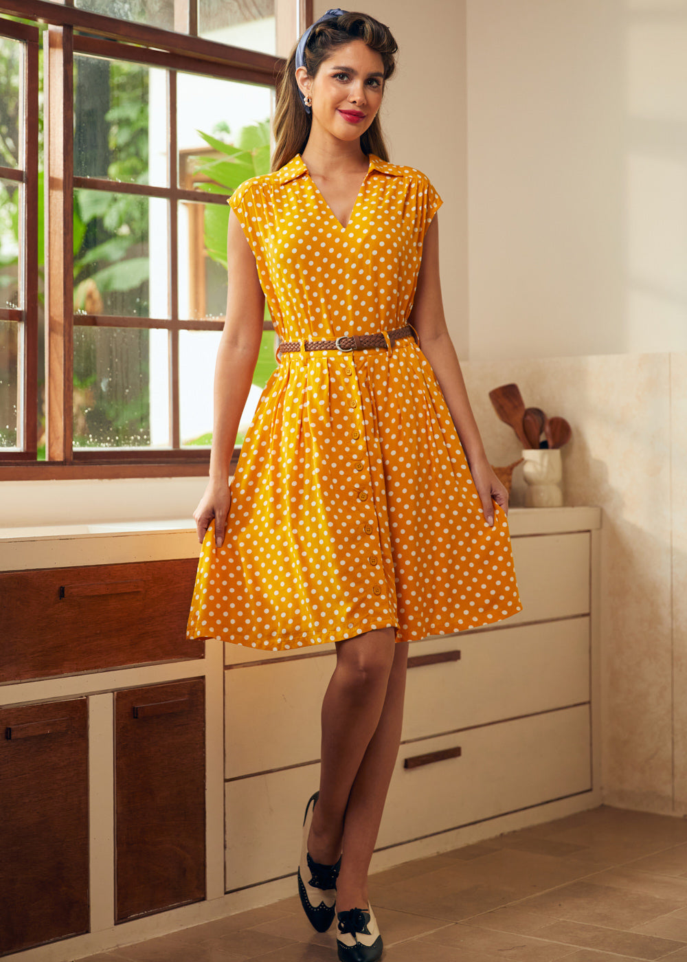 Woman styling retro-inspired yellow polka dot skirt with matching sleeveless top and vintage heels