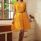 Woman styling retro-inspired yellow polka dot skirt with matching sleeveless top and vintage heels