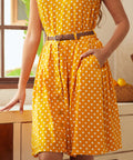 Woman wearing a yellow polka dot skirt with a belt in a kitchen setting